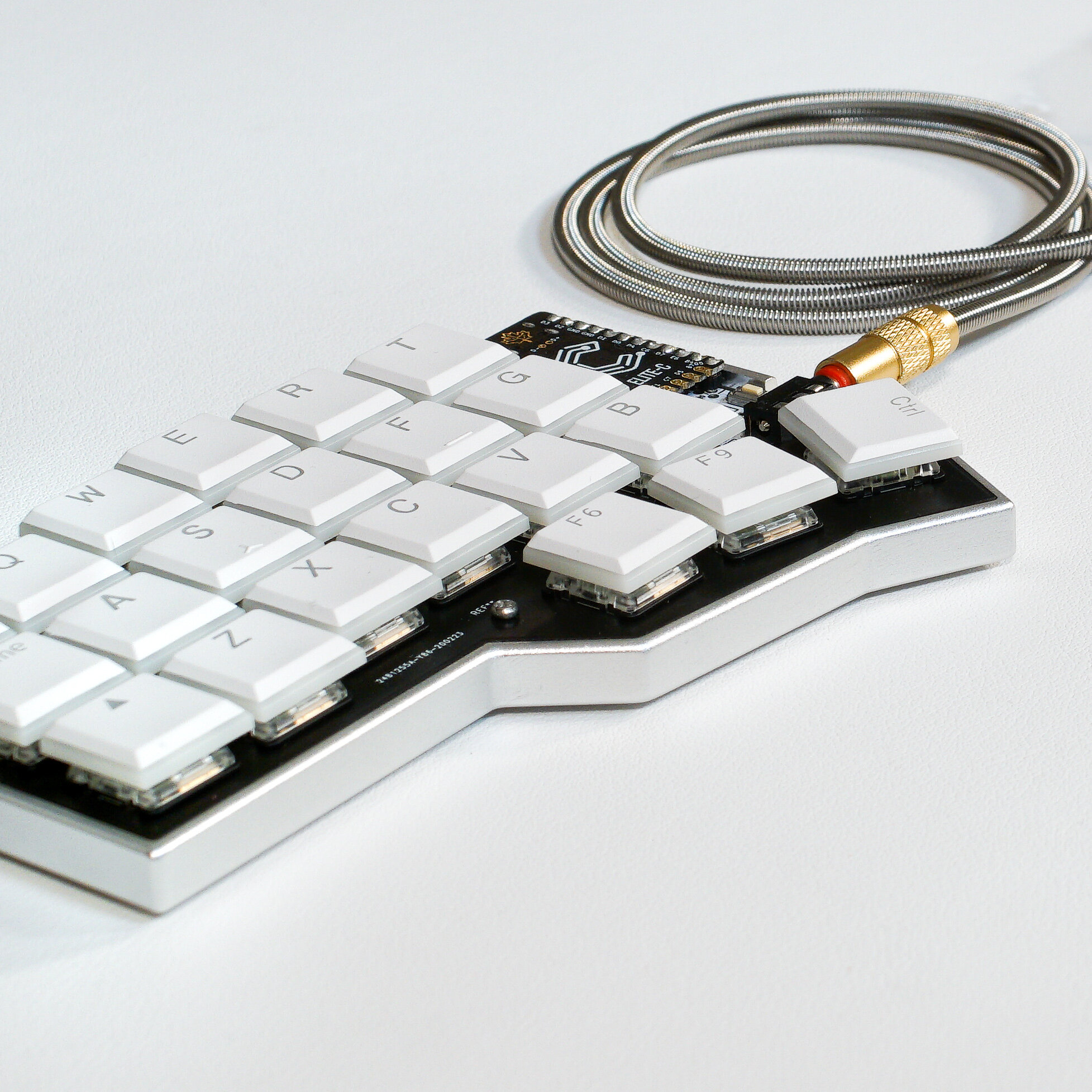 The Corne LP case in silver, with Kailh Choc white keycaps, an Elite C and a metal TRRS cable.